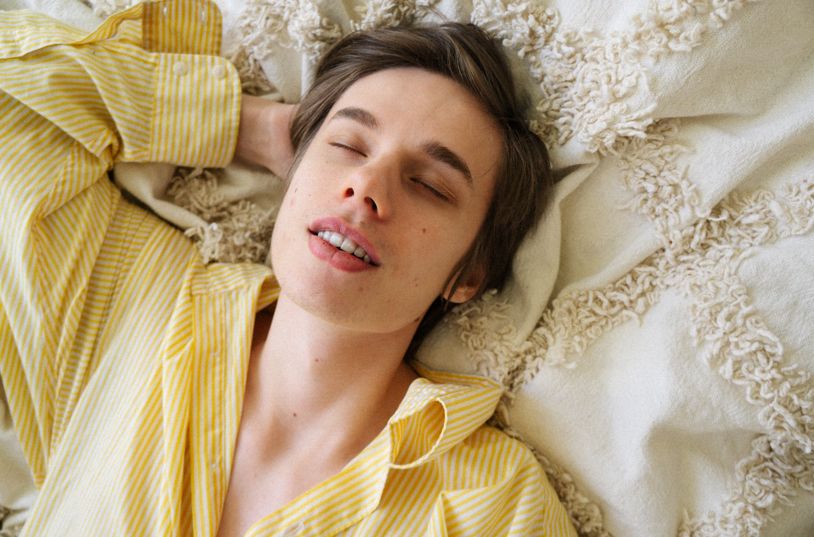 En person ligger i en säng, blundar och njuter.