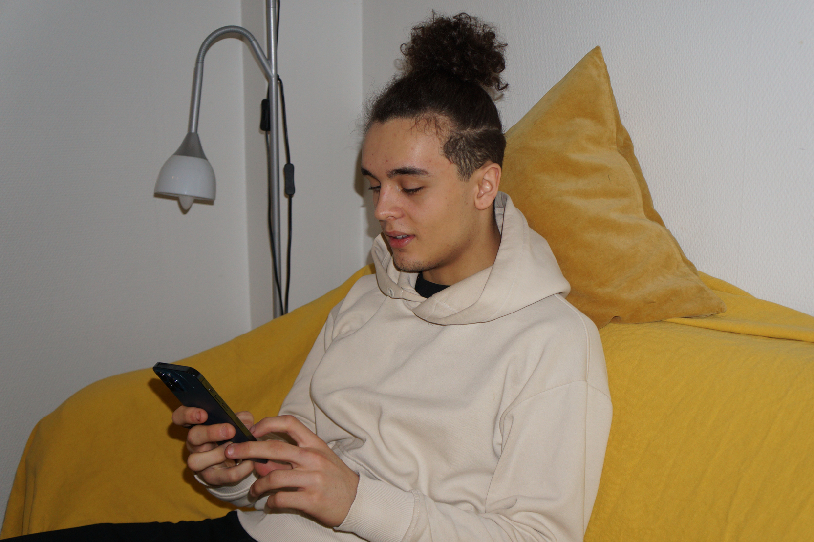 En kille som tittar i mobilen, glad.