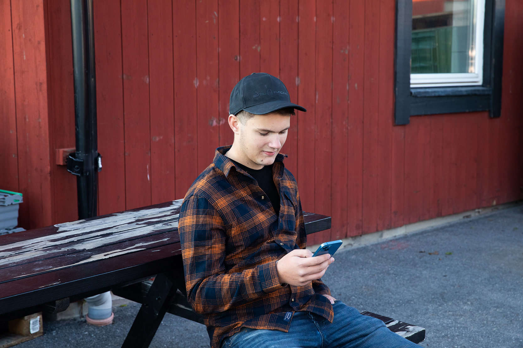 Kille sitter på en bänk och tittar på en telefon
