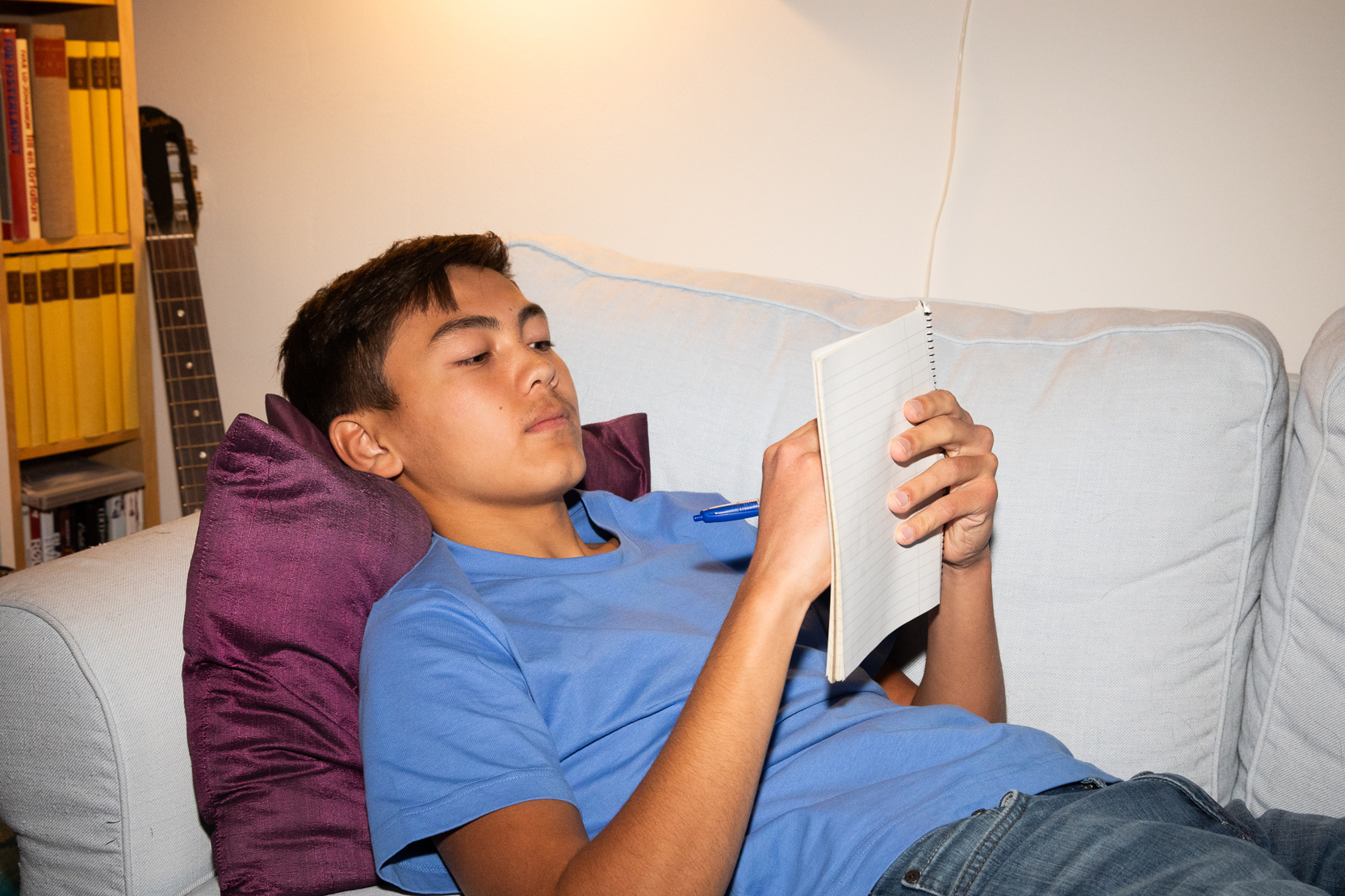 Kille ligger i soffan och akriver i ett skrivblock